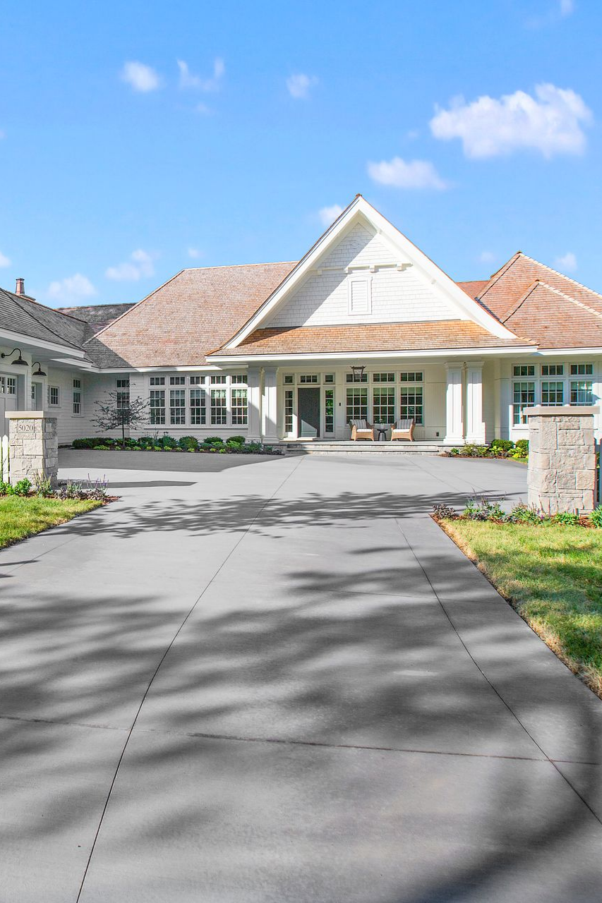 Blue-sided house with white garage door and concrete driveway on a sunny day.