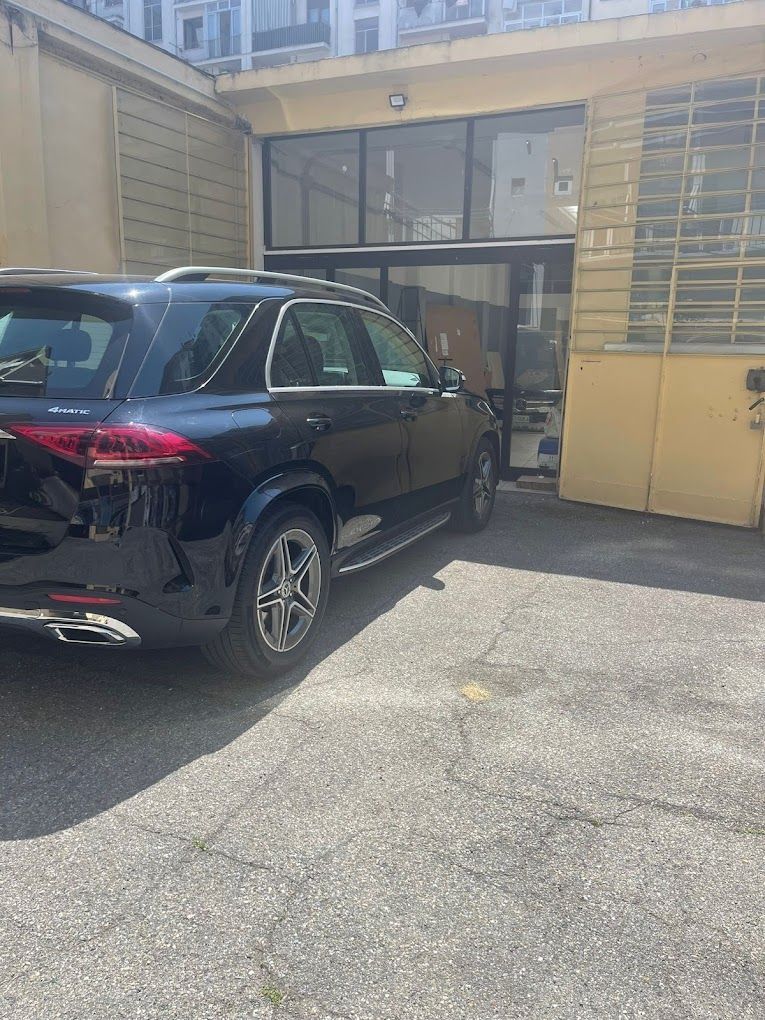 Un SUV nero è parcheggiato in un parcheggio di fronte a un edificio.