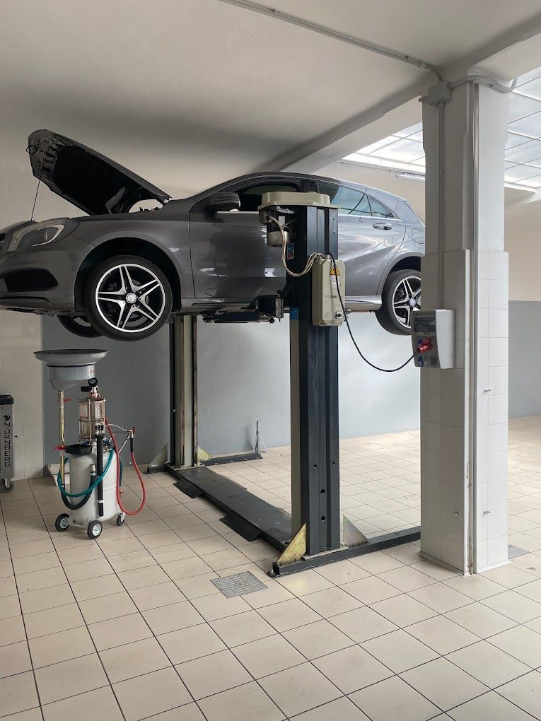 Un'auto è parcheggiata su un ponte sollevatore in un garage.