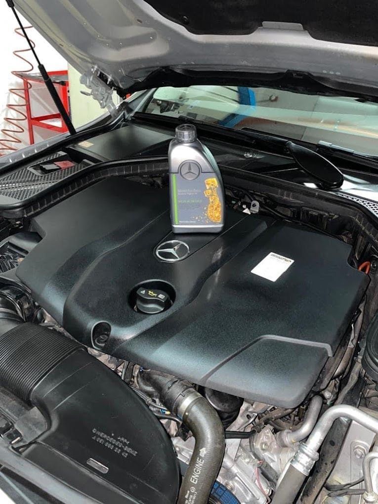 Una bottiglia di olio è appoggiata sul motore di un'auto.