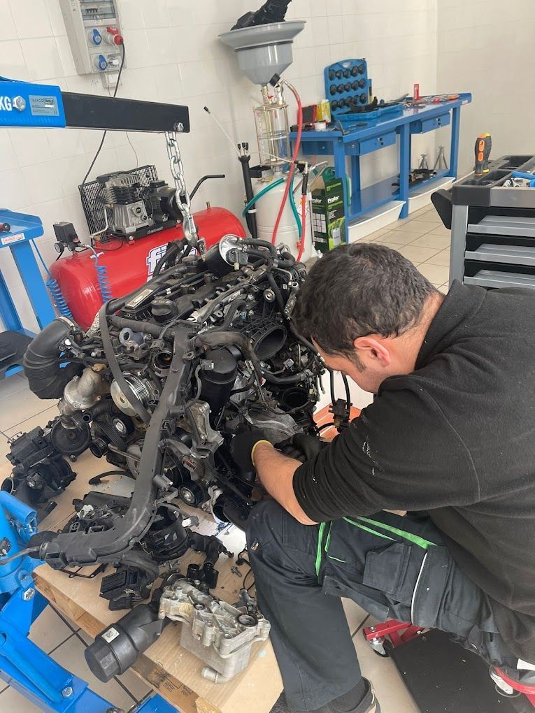 Un uomo sta lavorando sul motore di un'auto in un garage.