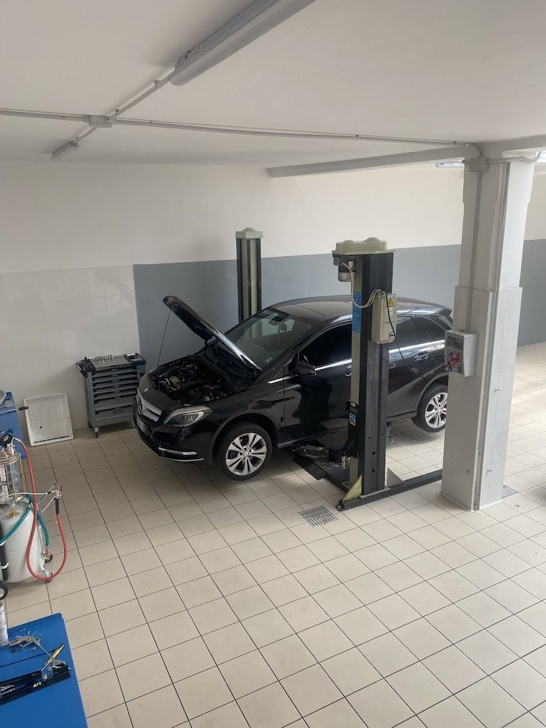 Un'auto nera è parcheggiata su un ponte elevatore in un garage.