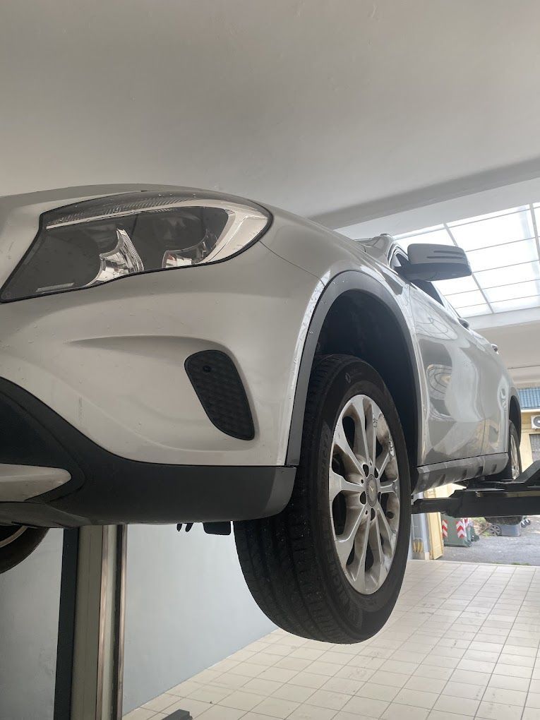 Un'auto bianca è parcheggiata su un ponte elevatore in un garage.