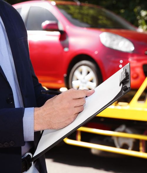 Un uomo tiene in mano un blocco per appunti davanti a un'auto rossa