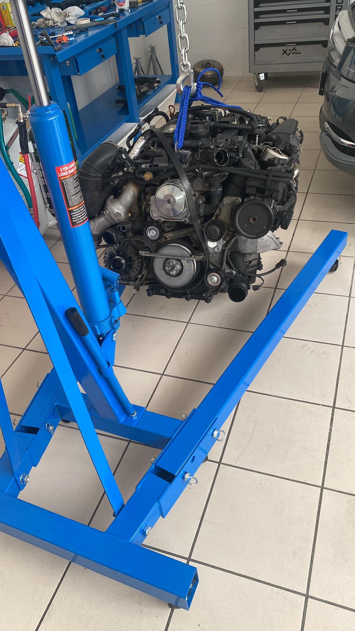 Un motore di automobile è appoggiato su un supporto blu in un garage.