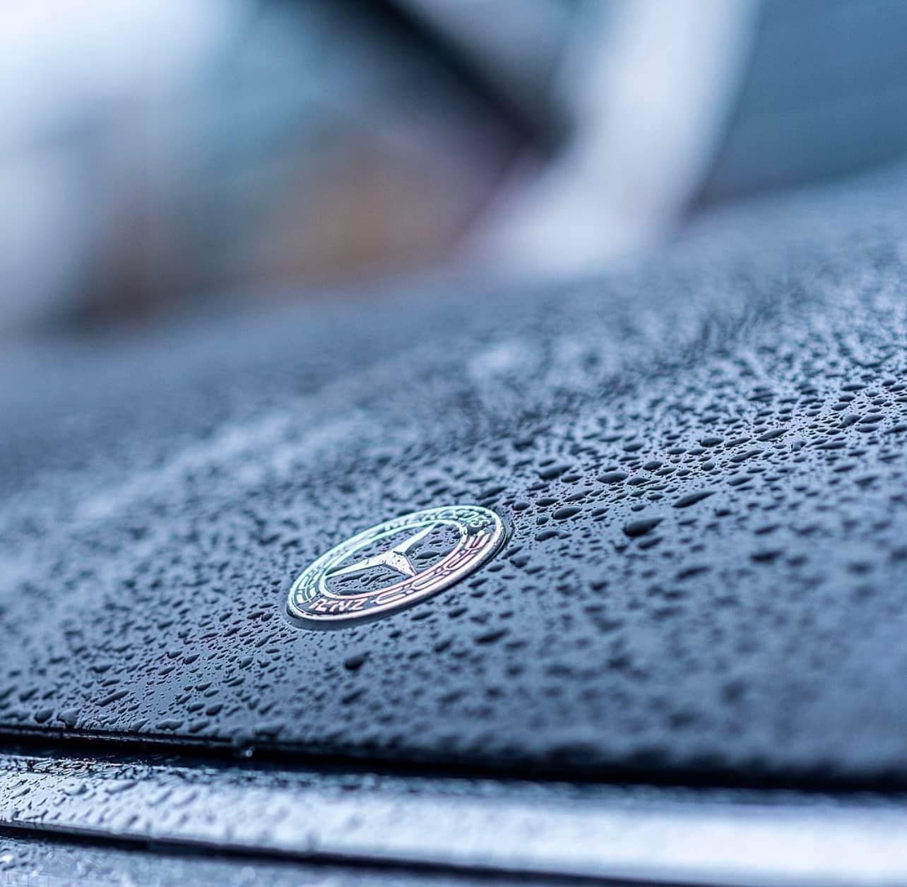 Primo piano del logo Mercedes Benz sul cofano di un'auto.