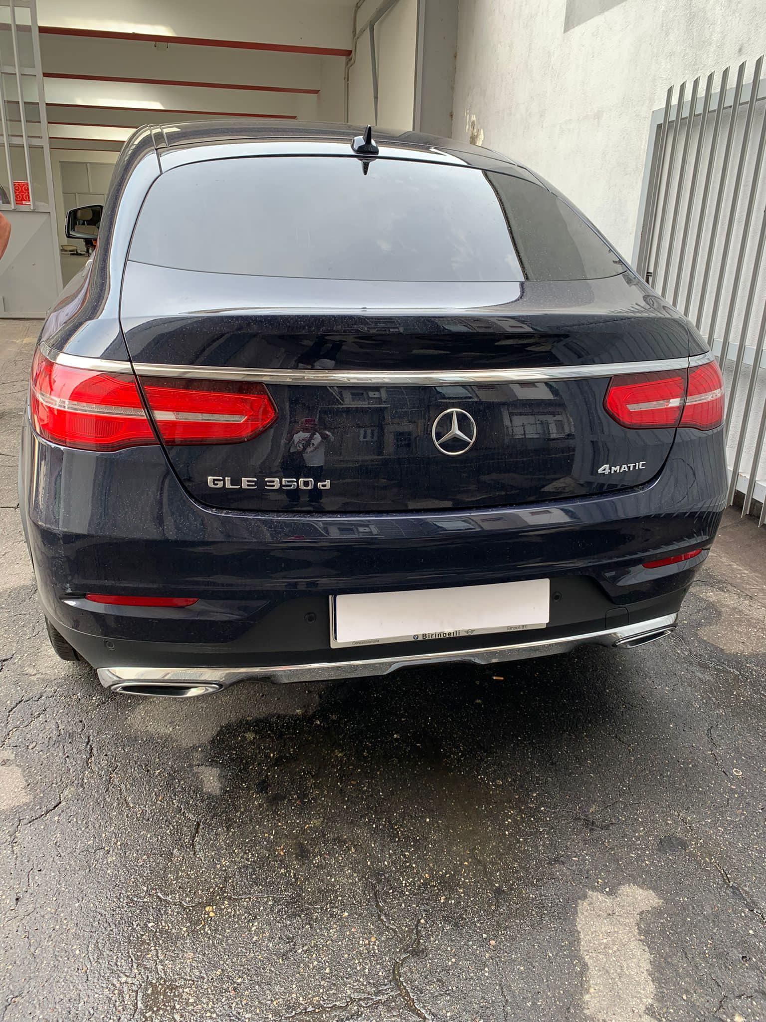 Una mercedes benz gle 450 nera è parcheggiata davanti a un edificio.