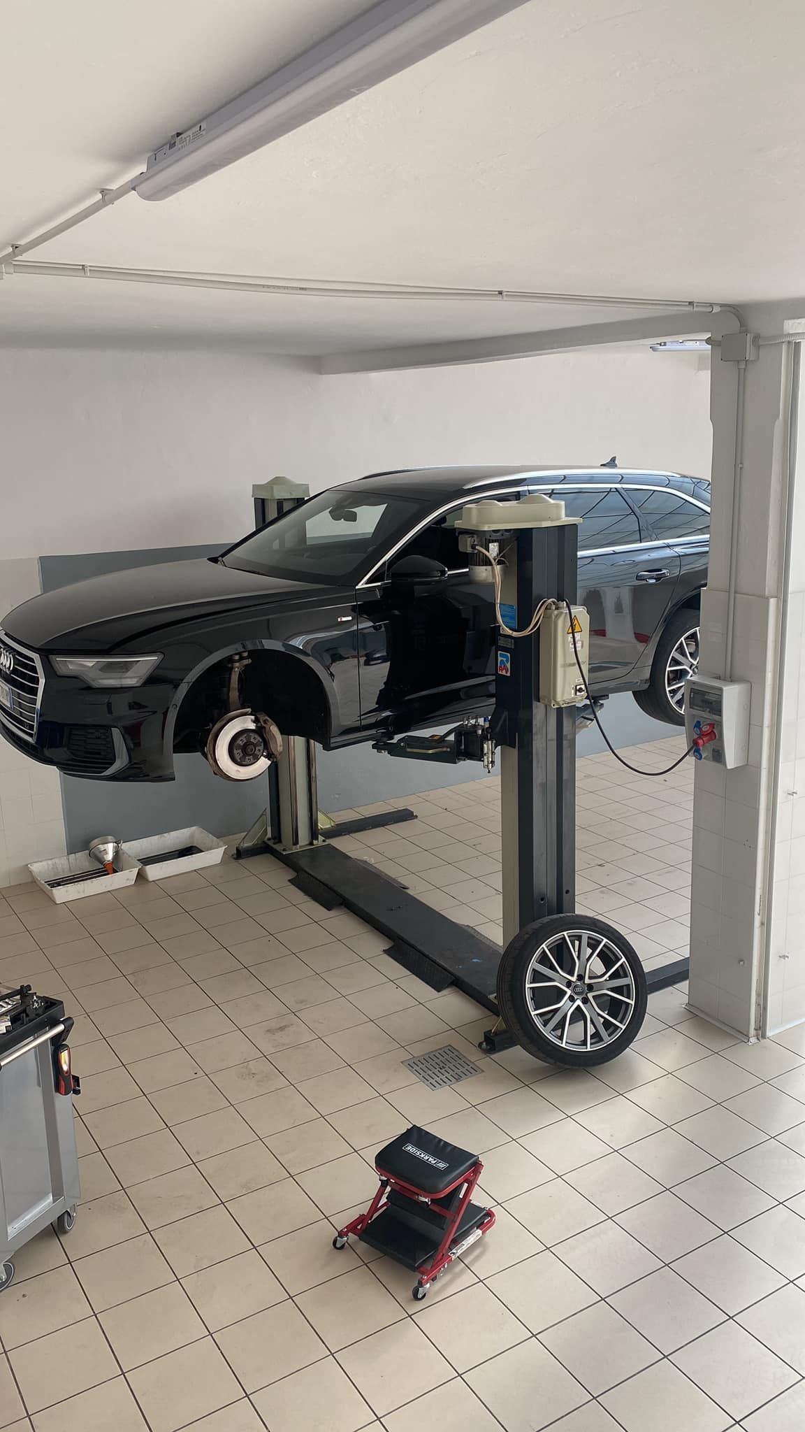 Un'auto è parcheggiata su un ponte sollevatore in un garage.