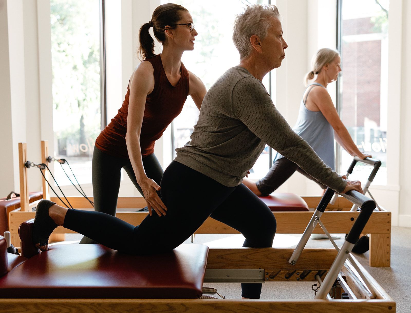 A woman is helping a man do stretching exercises on a pilates reformer