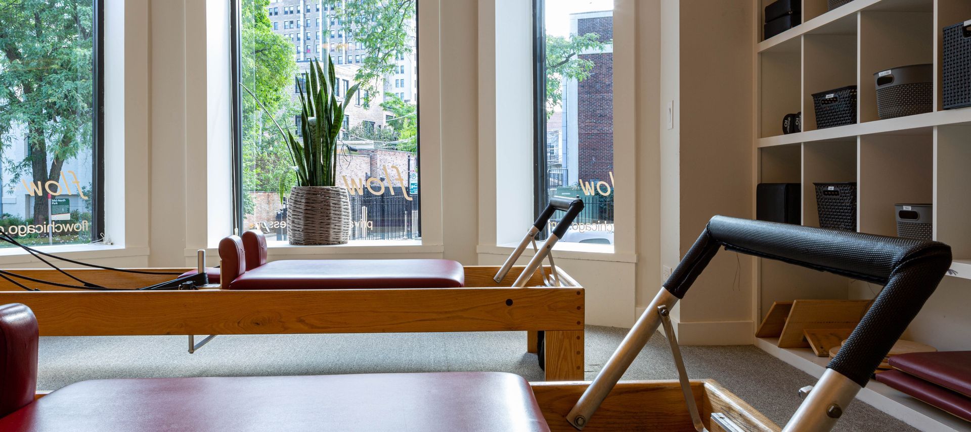 A pilates reformer is sitting in a room next to a window.