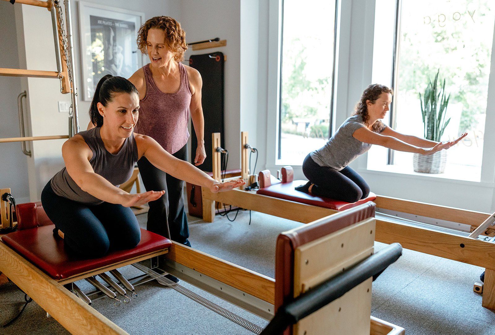 two women are doing pilates on a pilates machine in a gym .