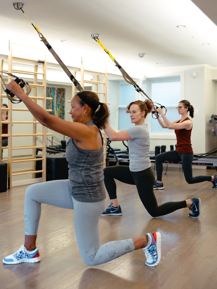 A group of women are doing trx exercises