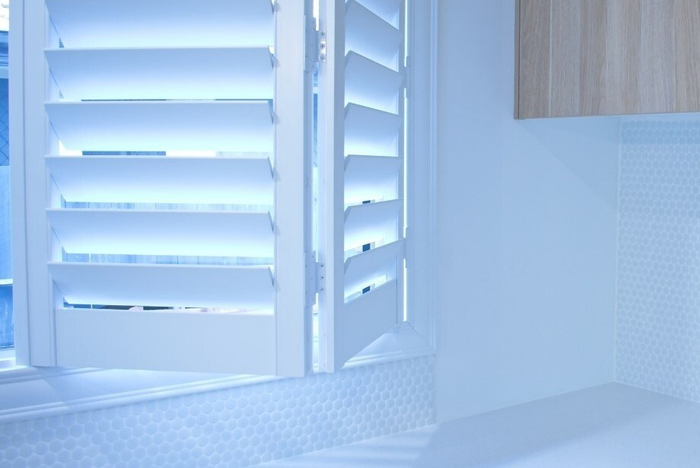 Close up of folding plantation shutters in kitchen setting, backed by timber cupboard.