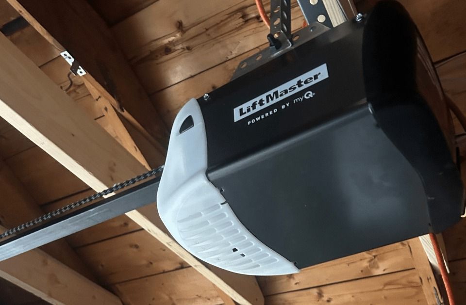 A garage door opener is hanging from the ceiling of a wooden garage.