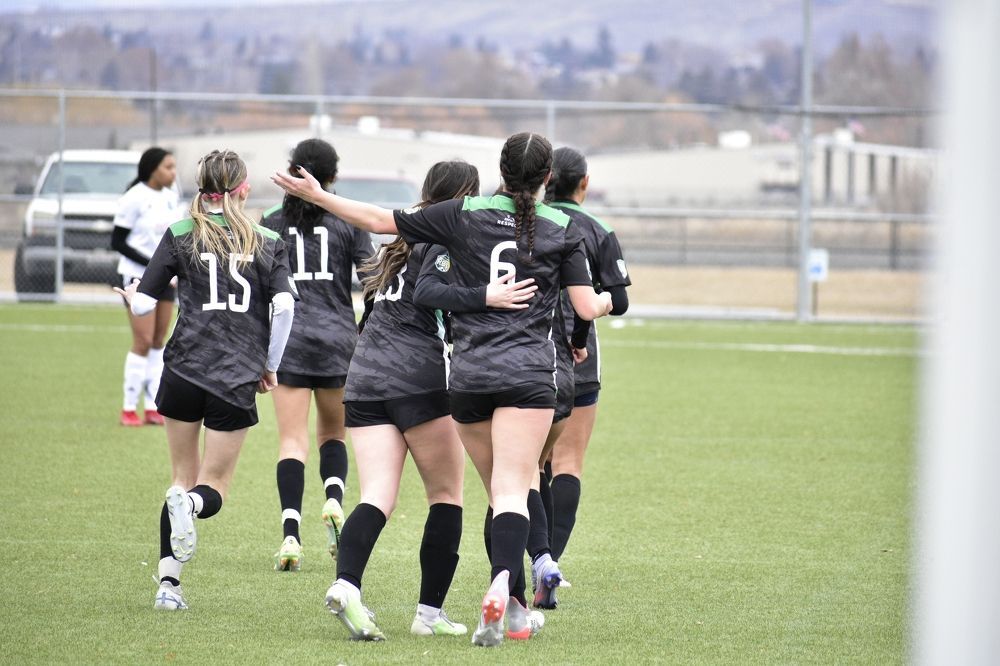 A group of female soccer players are hugging each other on a field.