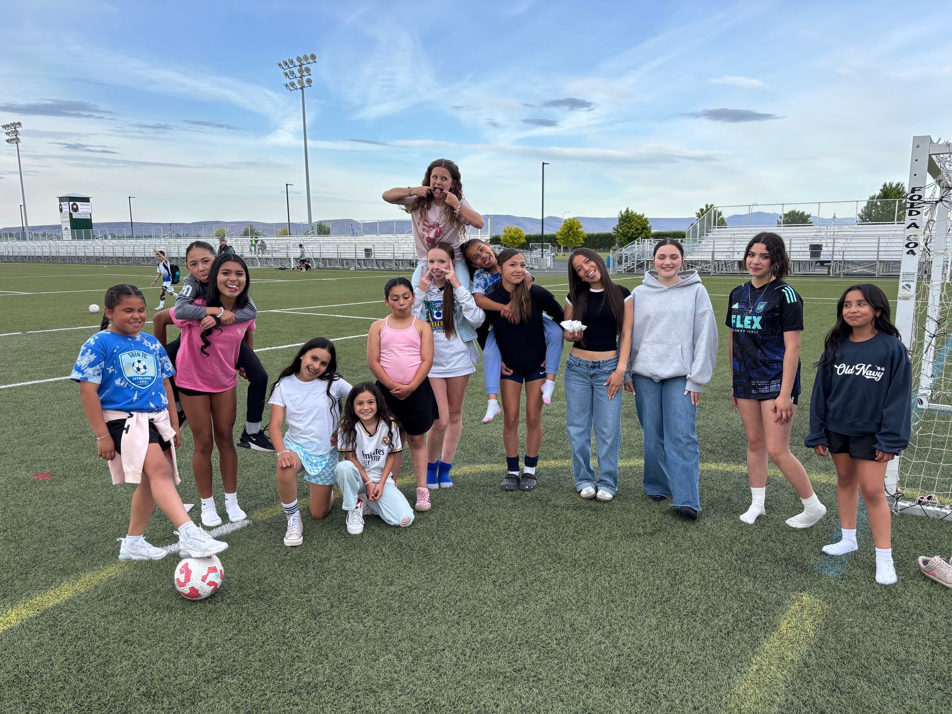 A group of young girls are posing for a picture on a soccer field.