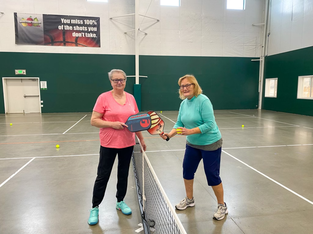Two women are playing paddle tennis on a court