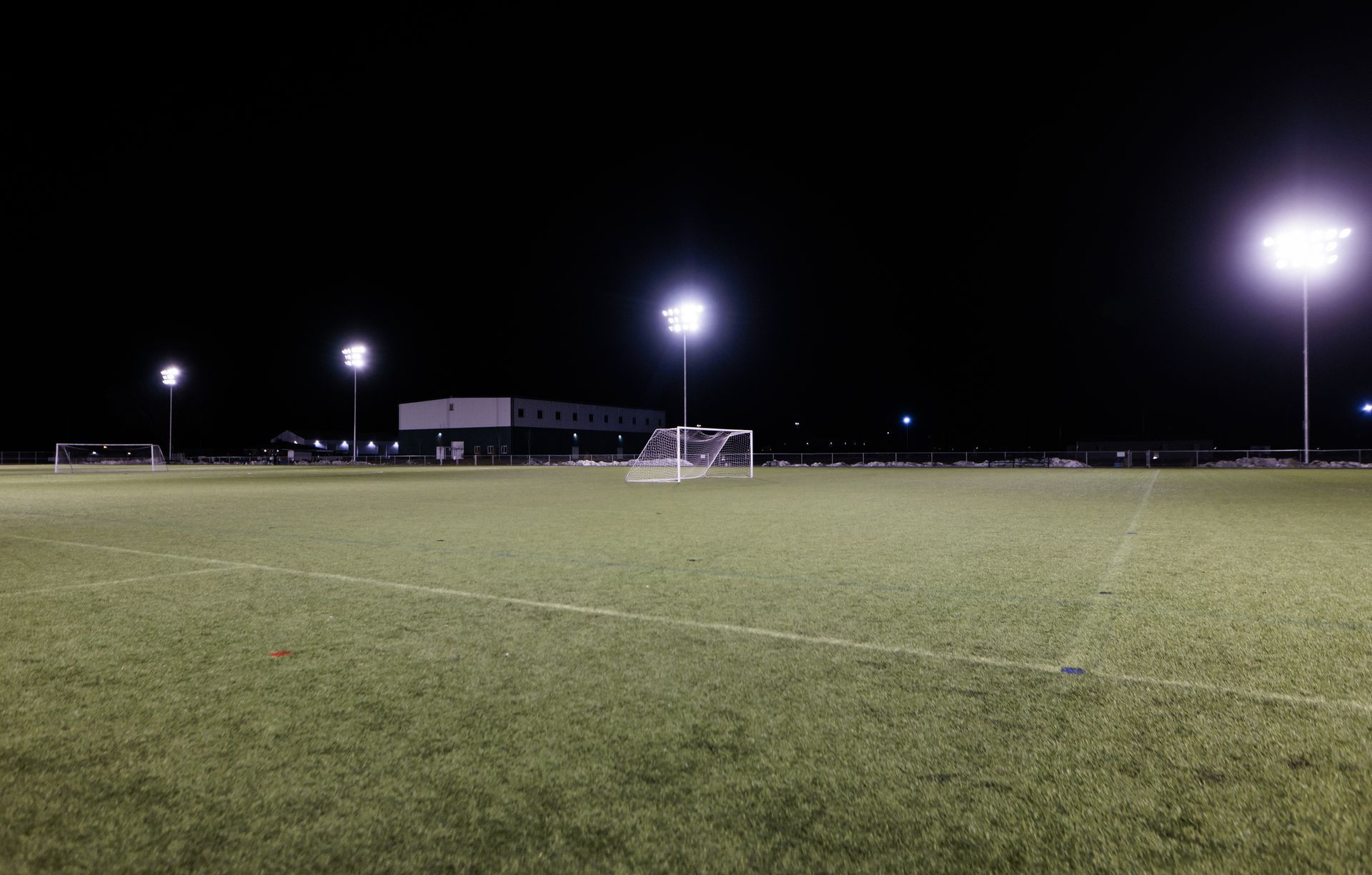 A soccer field is lit up at night with a goal.