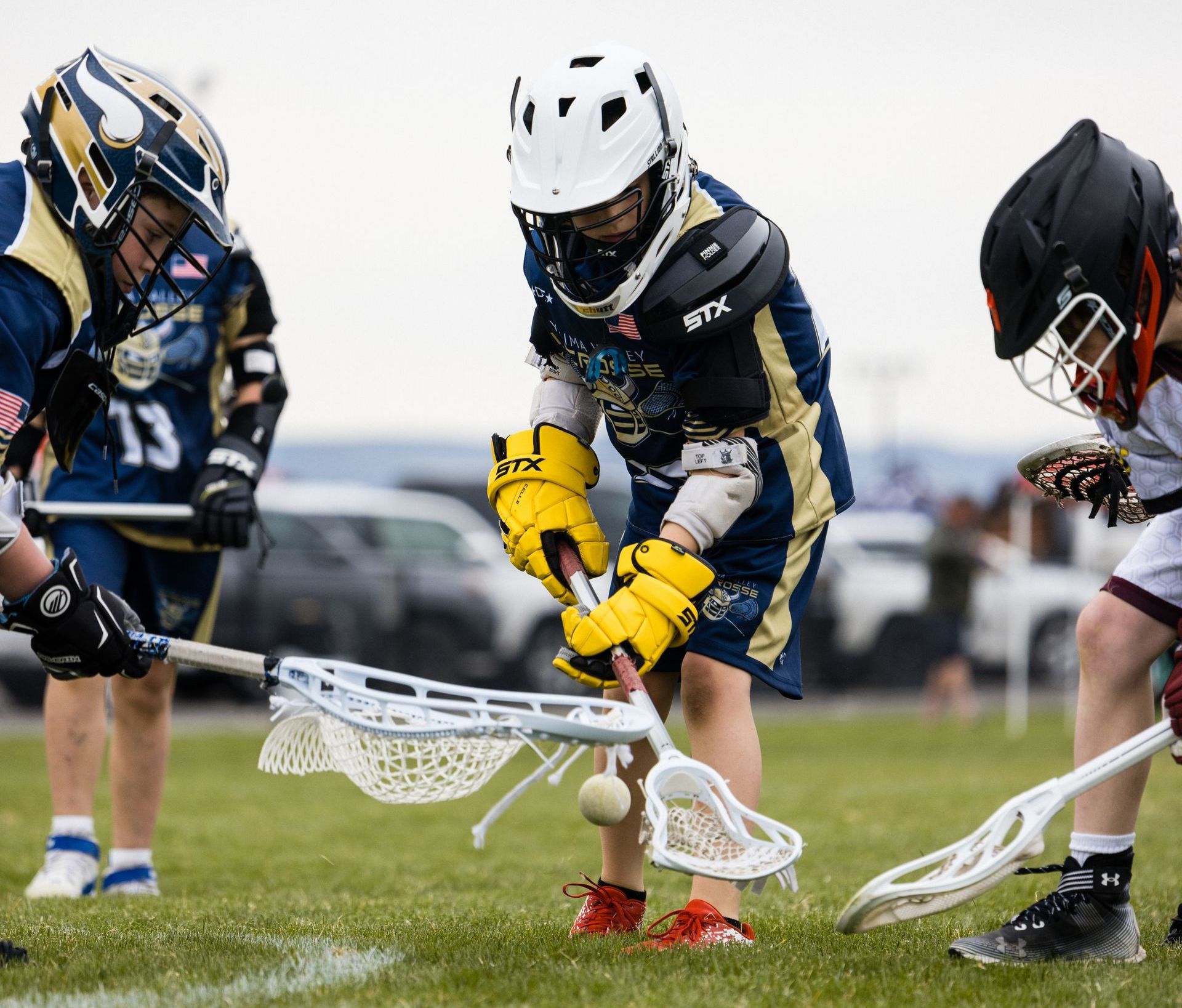 A group of young boys are playing lacrosse on a field.