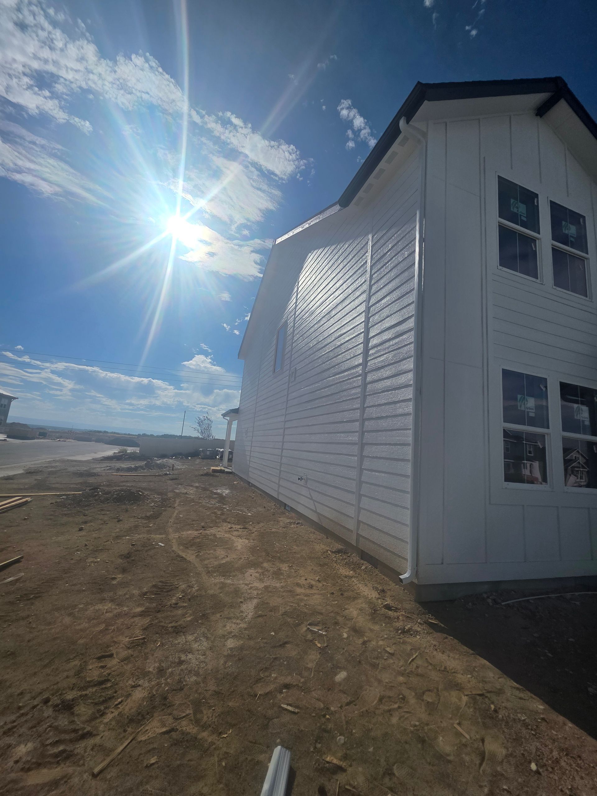 White house under construction, bright sun, blue sky, and dirt ground.