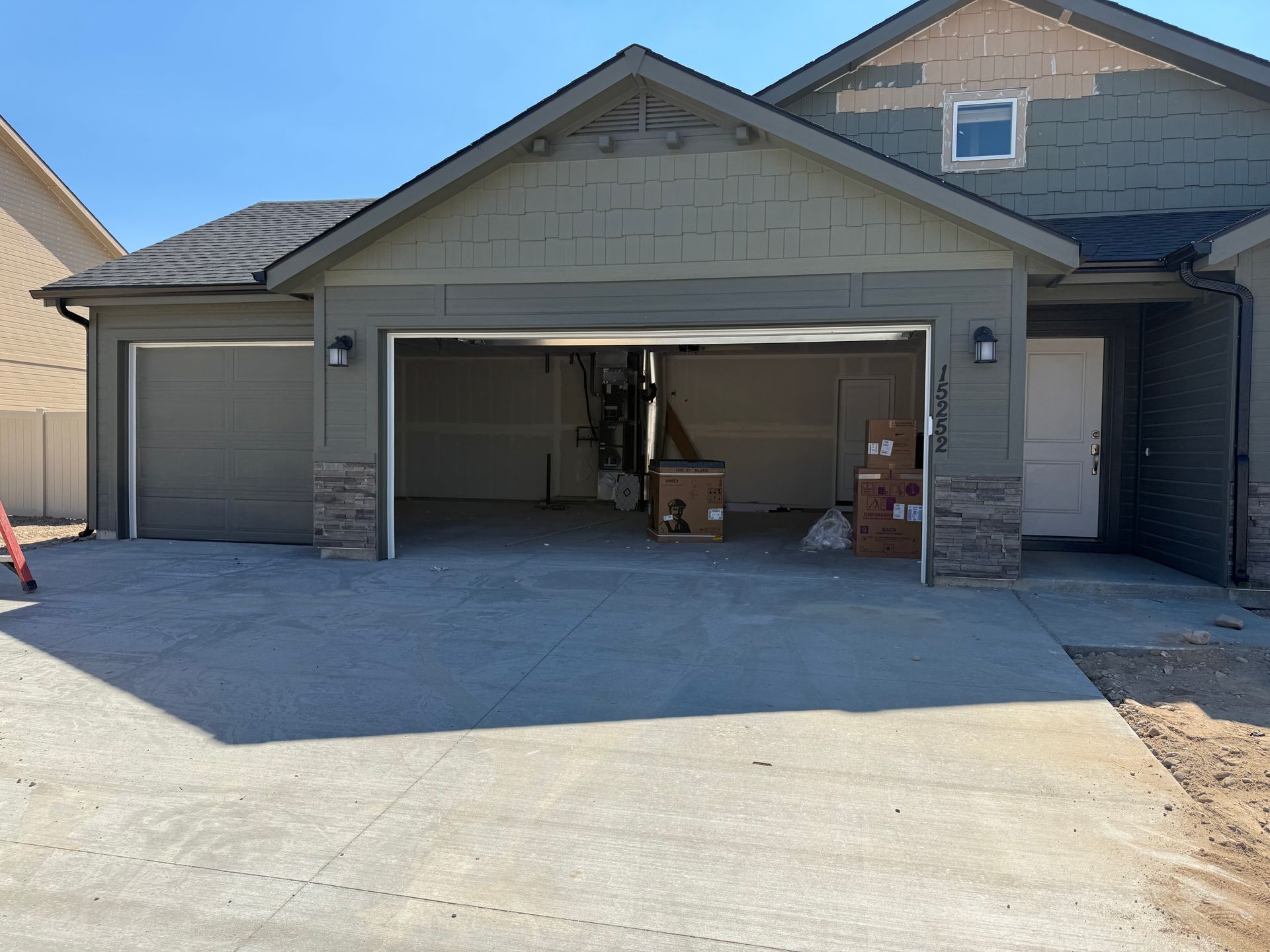 House exterior with three-car garage. The center garage door is open, revealing items inside. Concrete driveway.