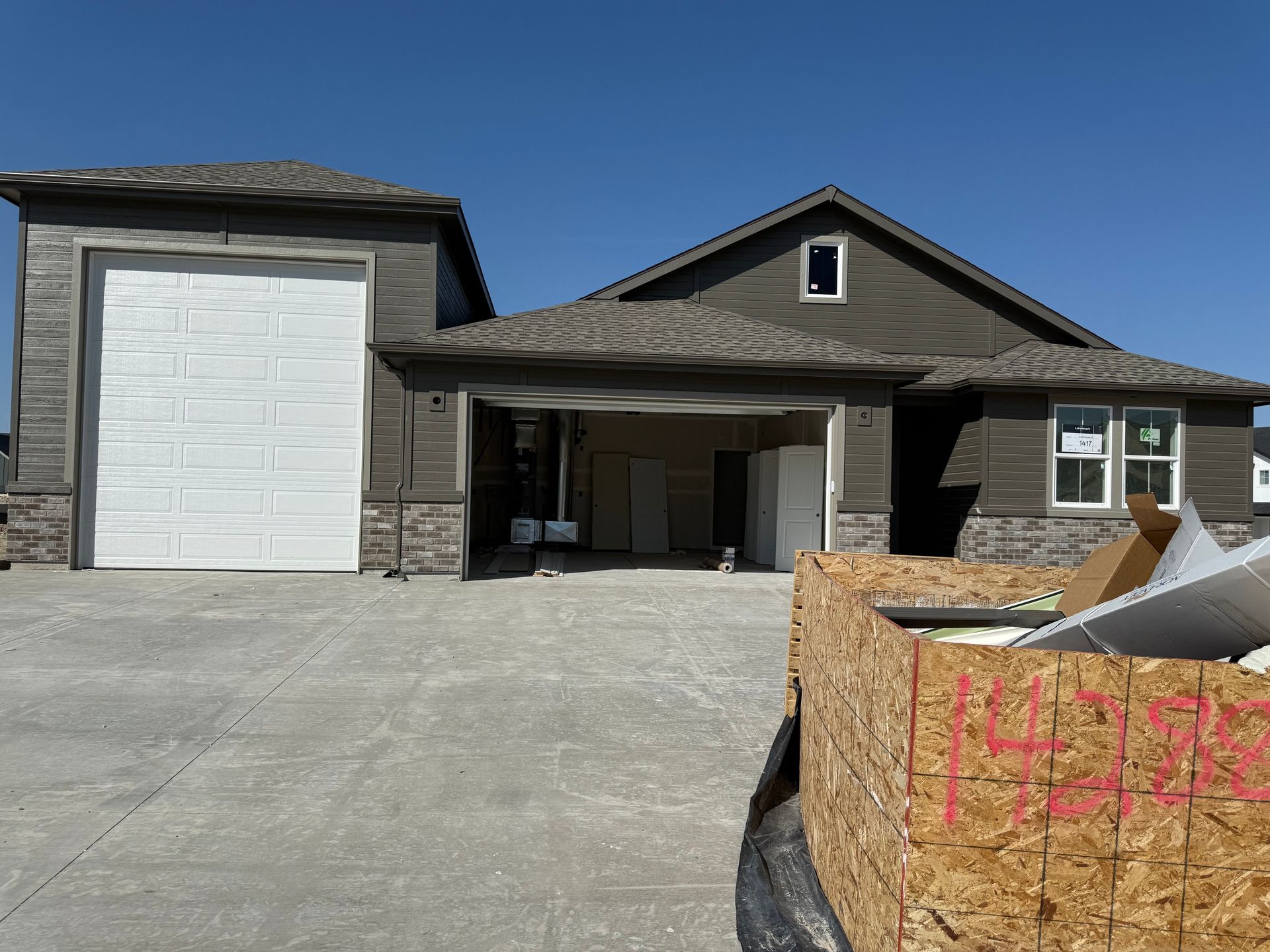 New house under construction with a garage, siding, and a white garage door.