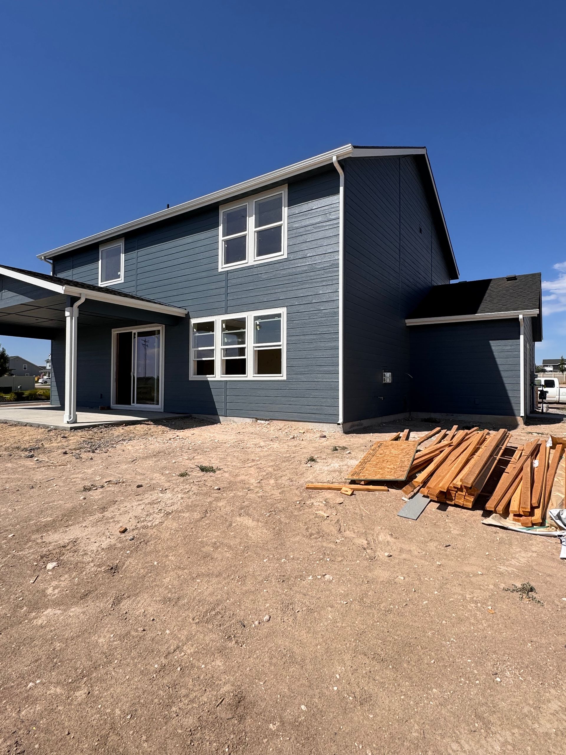 Two-story house with blue siding, white trim, and a covered patio