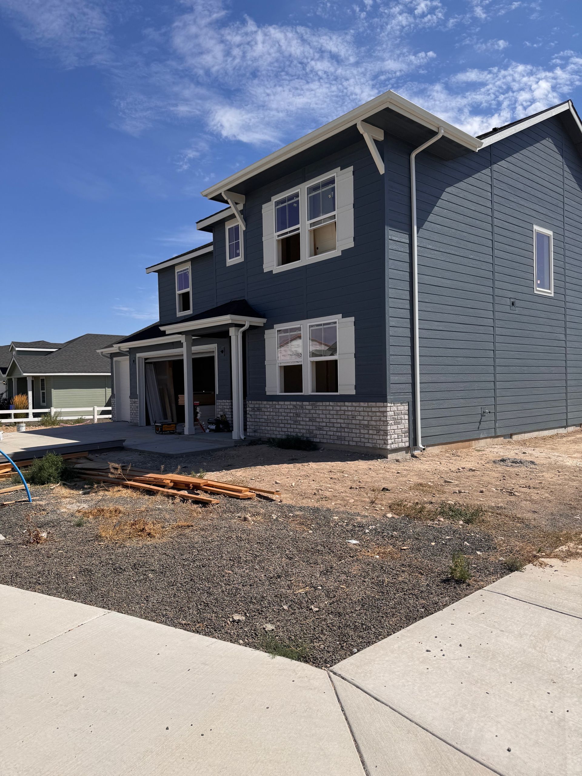 Two-story blue house under construction with white trim and stone accents.