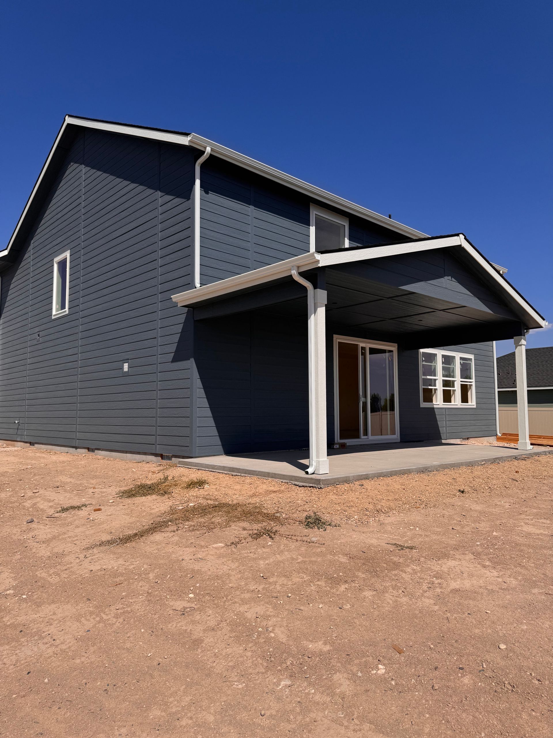Blue-sided house with a covered patio on a sunny day.