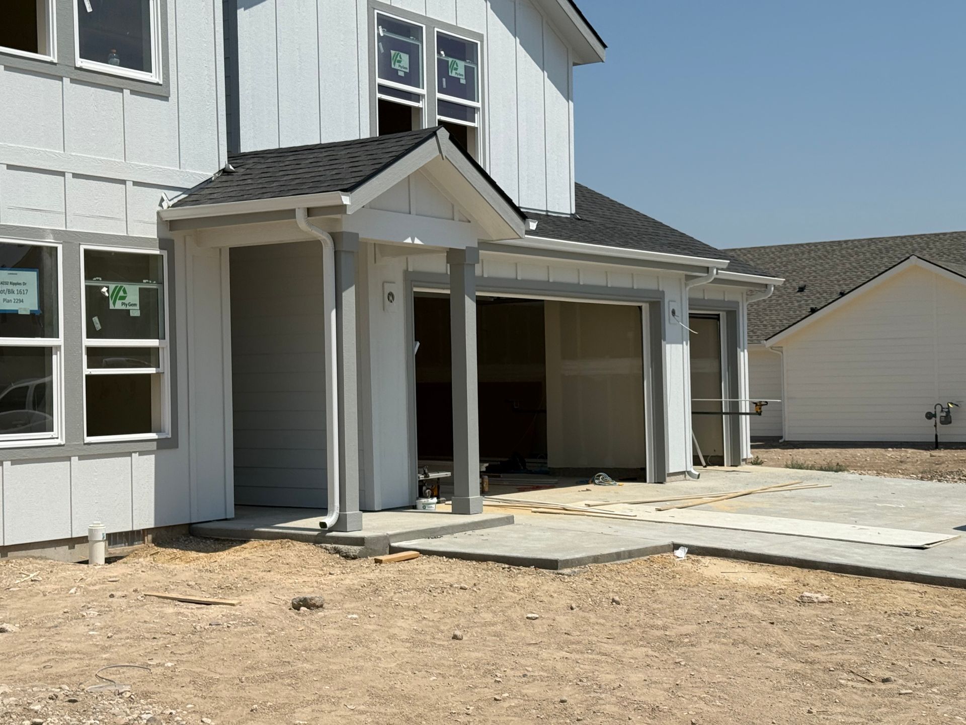A two-story house under construction with a covered entranceway and light blue siding.