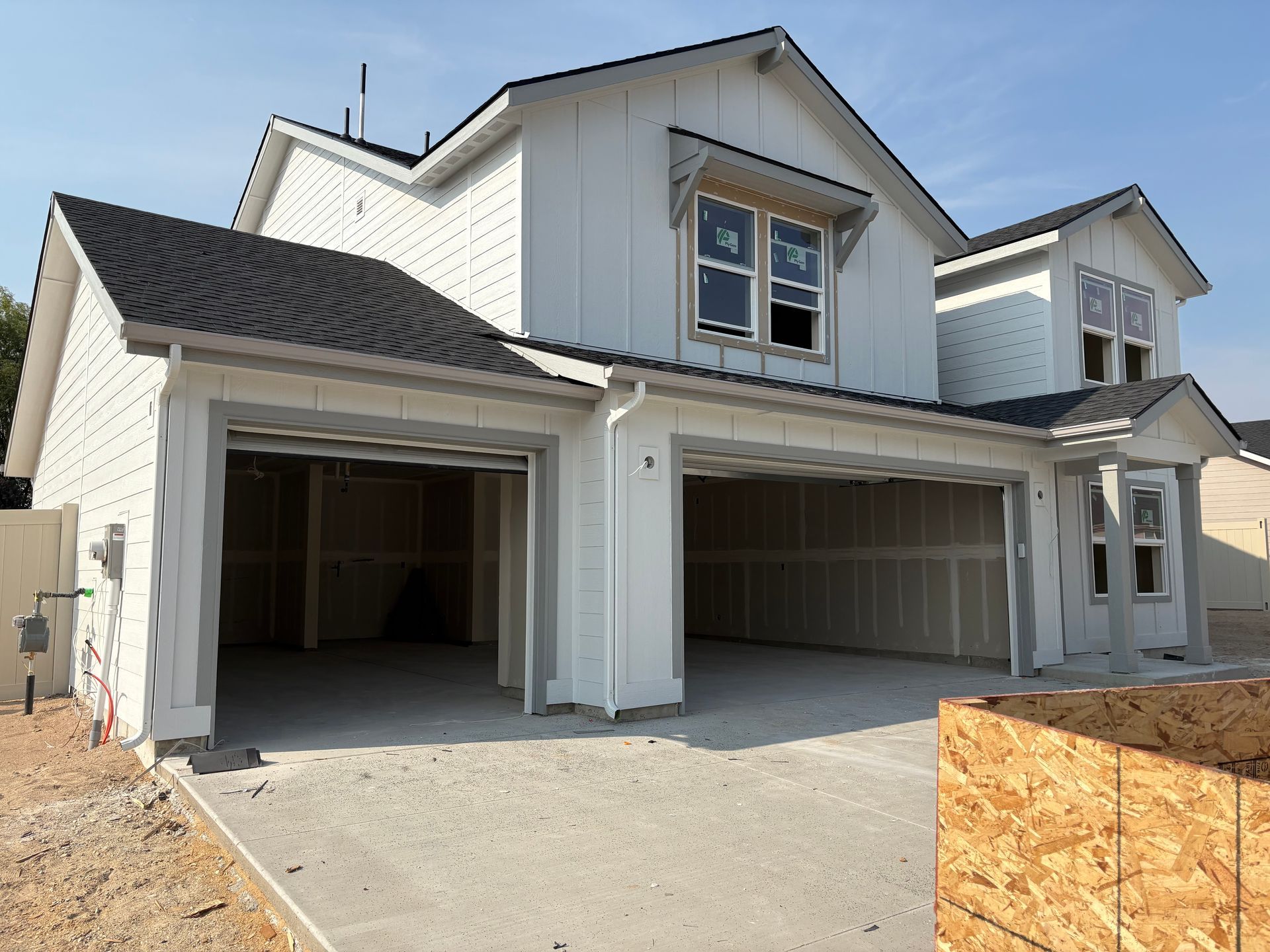 Two-story white house under construction with an open two-car garage.