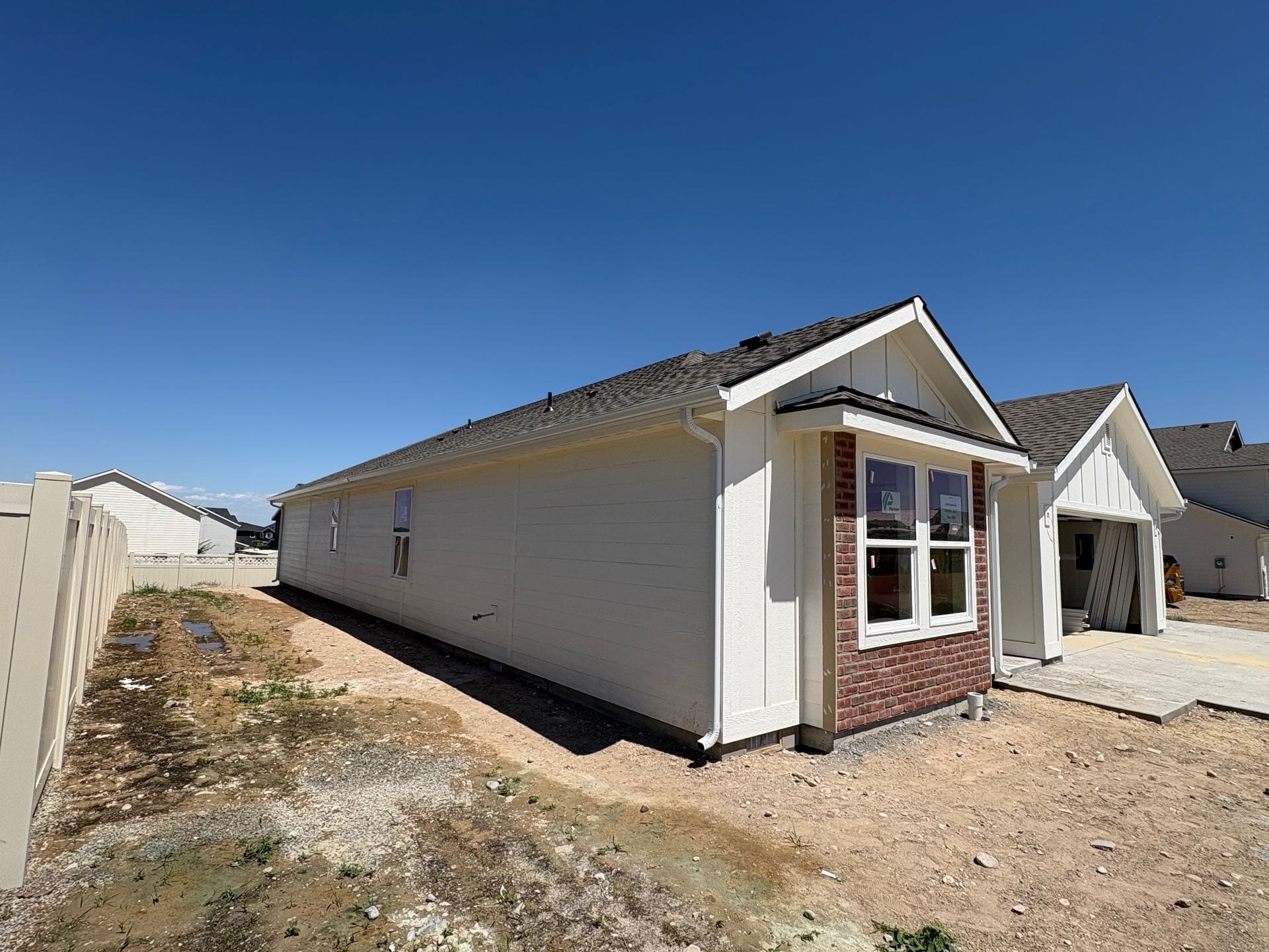 White house under construction with brick accents and clear blue sky.