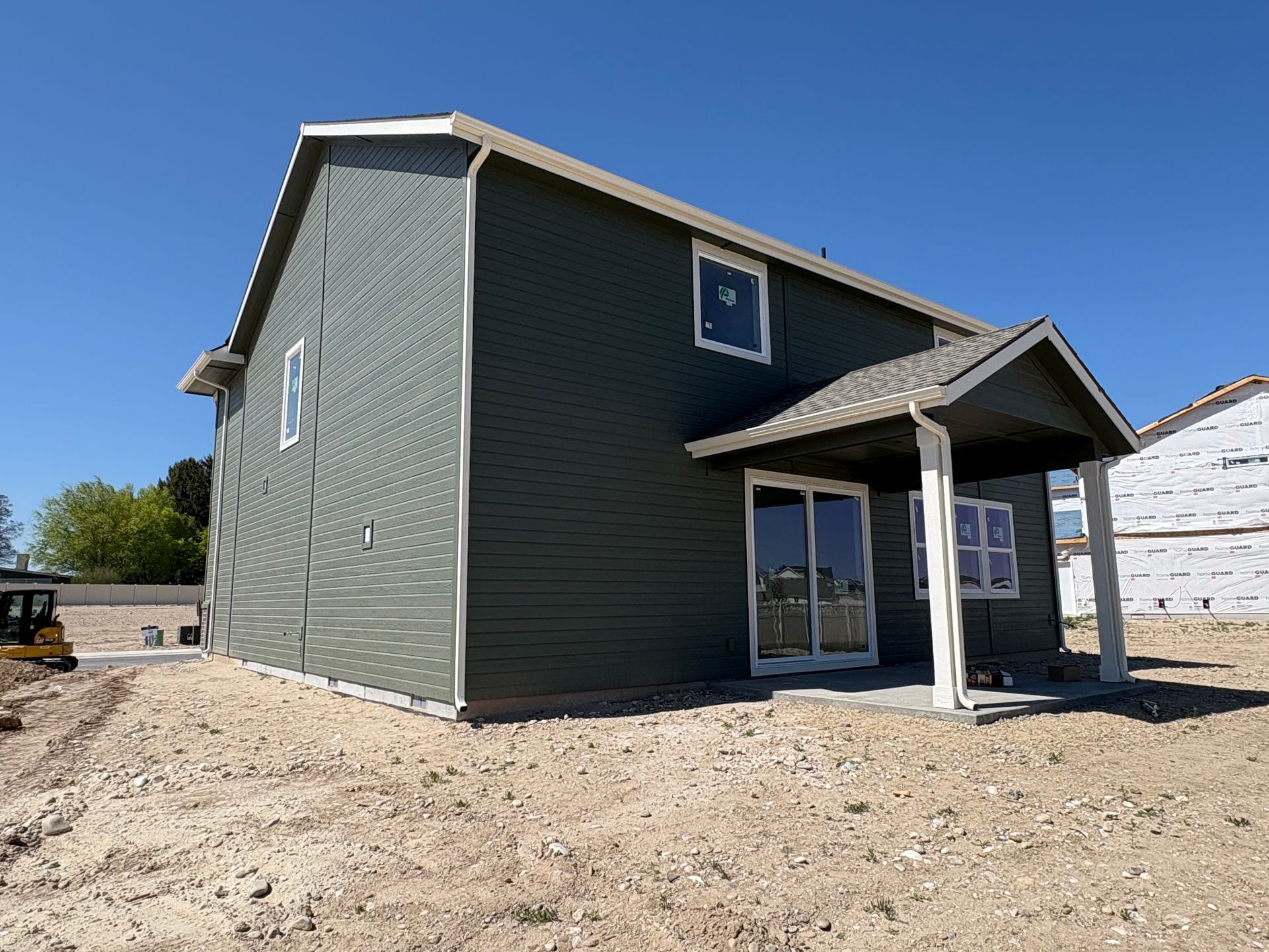 Green house under construction with light-colored trim and covered porch.