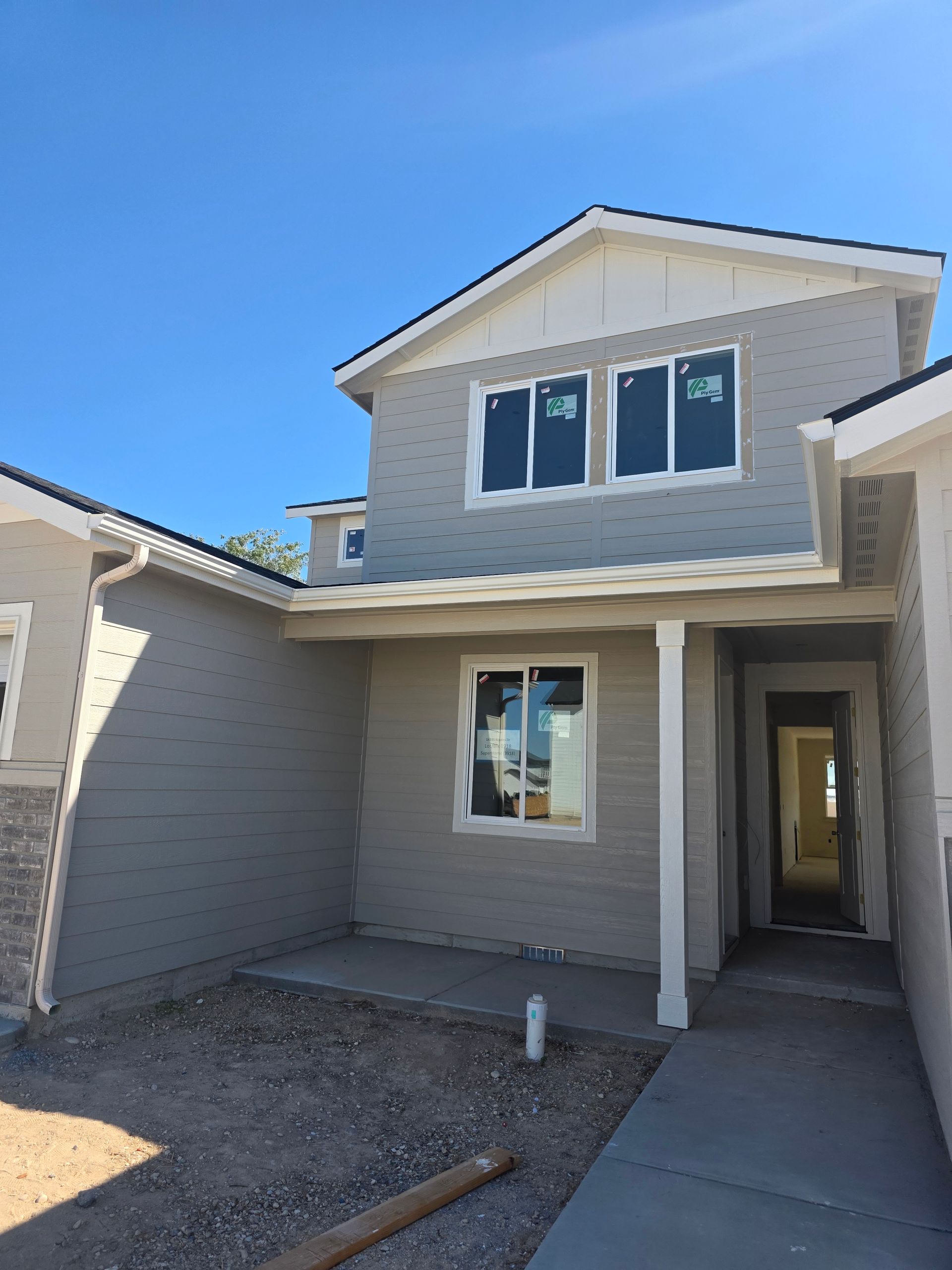 Gray two-story house with white trim under a clear blue sky.