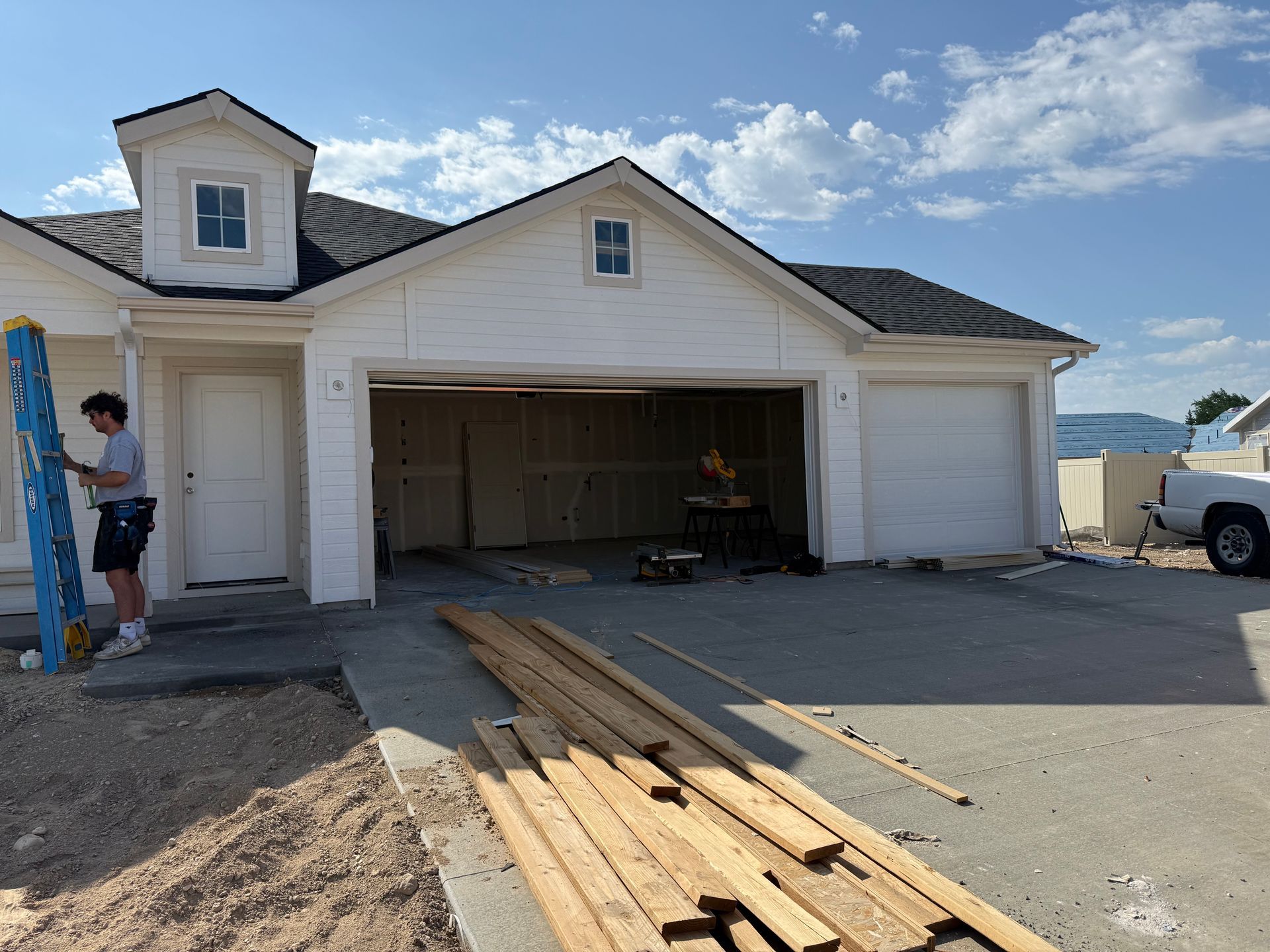 Man using level at a garage under construction; wood planks on the ground.
