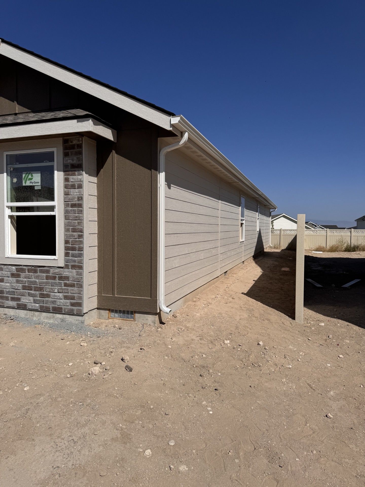 Exterior of a house with beige siding, white gutters, and a blue sky.