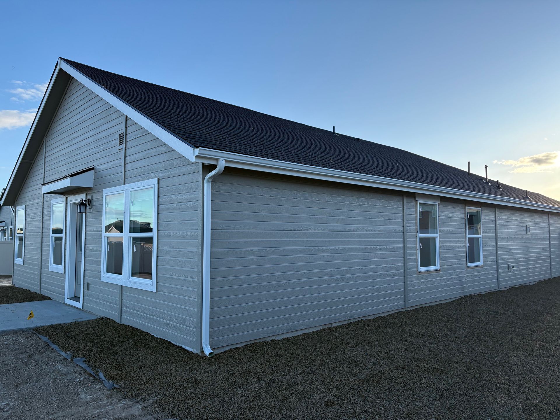 Beige modular building with white trim, windows, and dark roof under a blue sky.