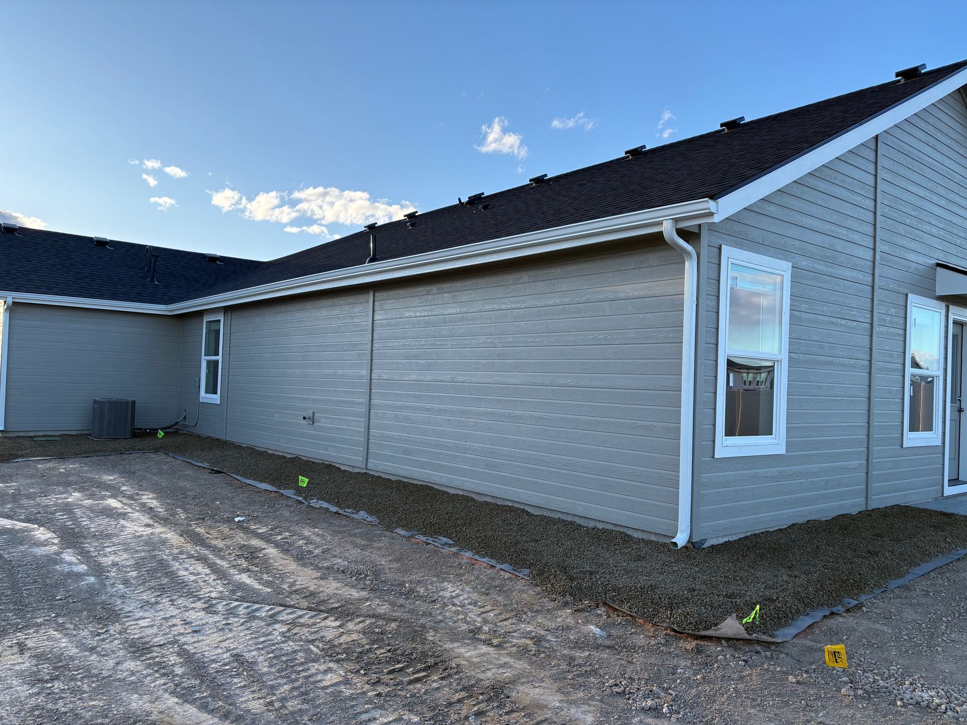 Exterior view of a house with gray siding, white trim, and a black roof.
