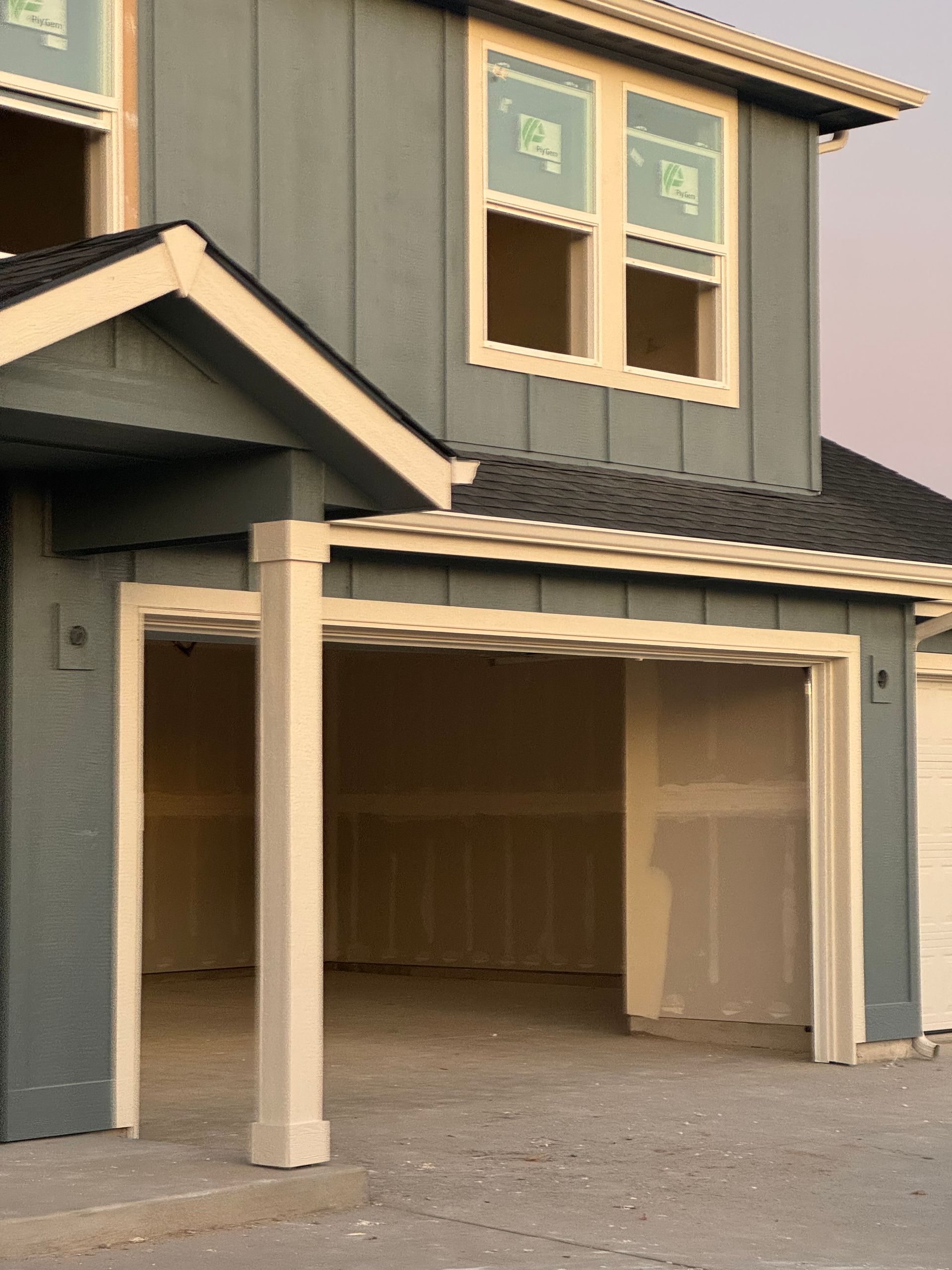 Two-story house with a blue exterior and open garage. Windows are visible on the second floor.