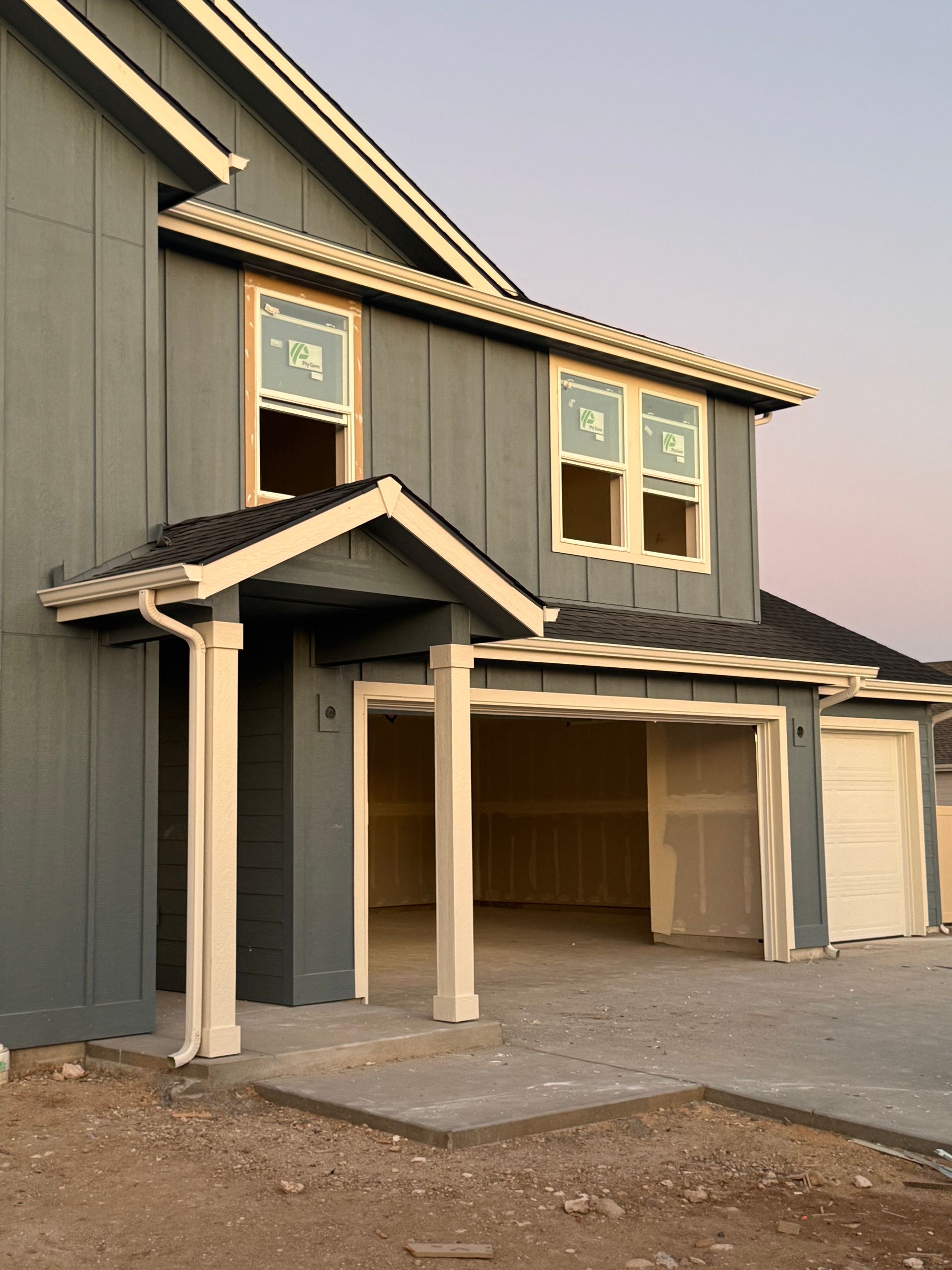 New construction two-story house with blue siding, white trim, and an open garage.