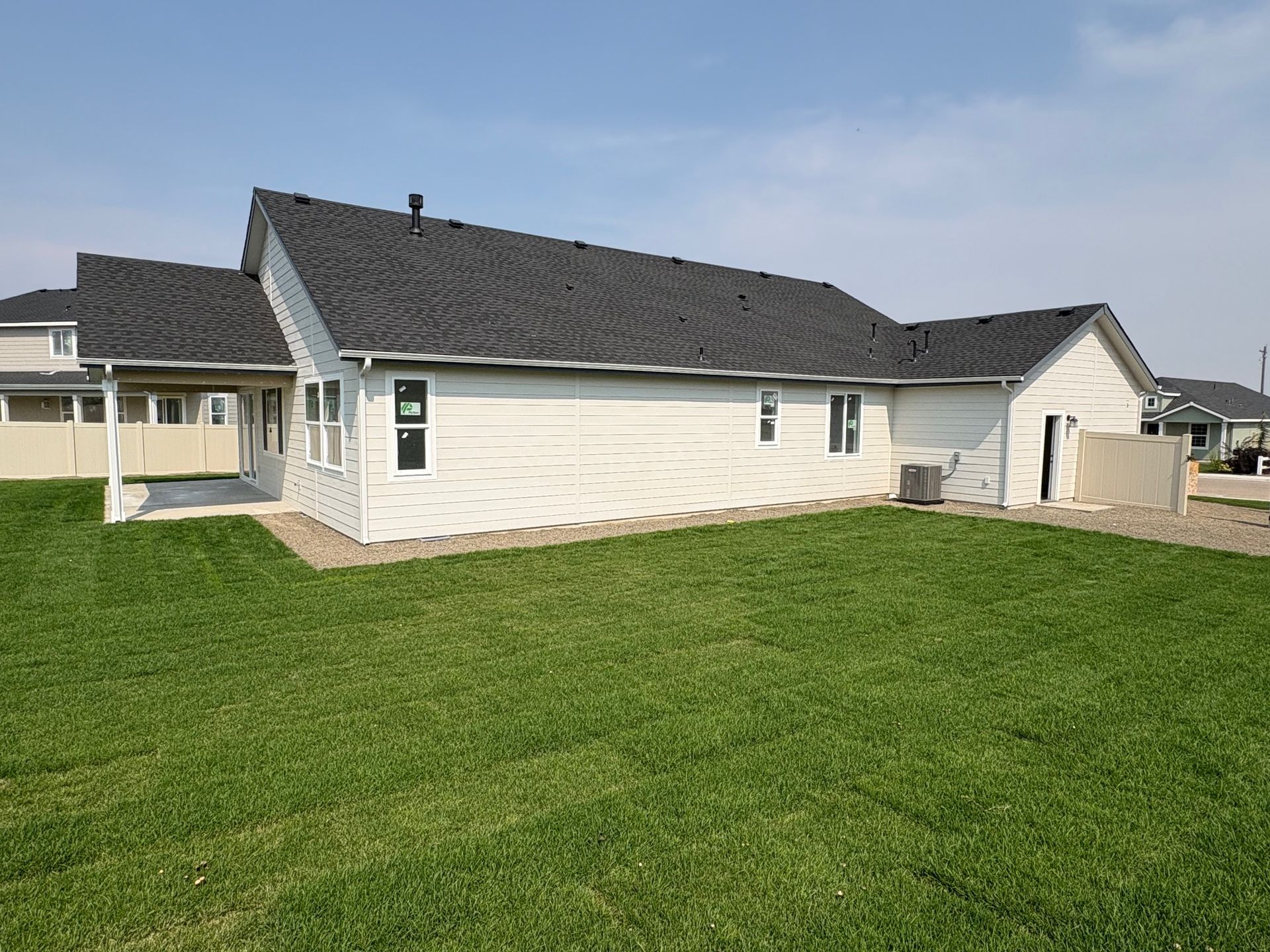 White house with dark roof and green lawn on a sunny day.