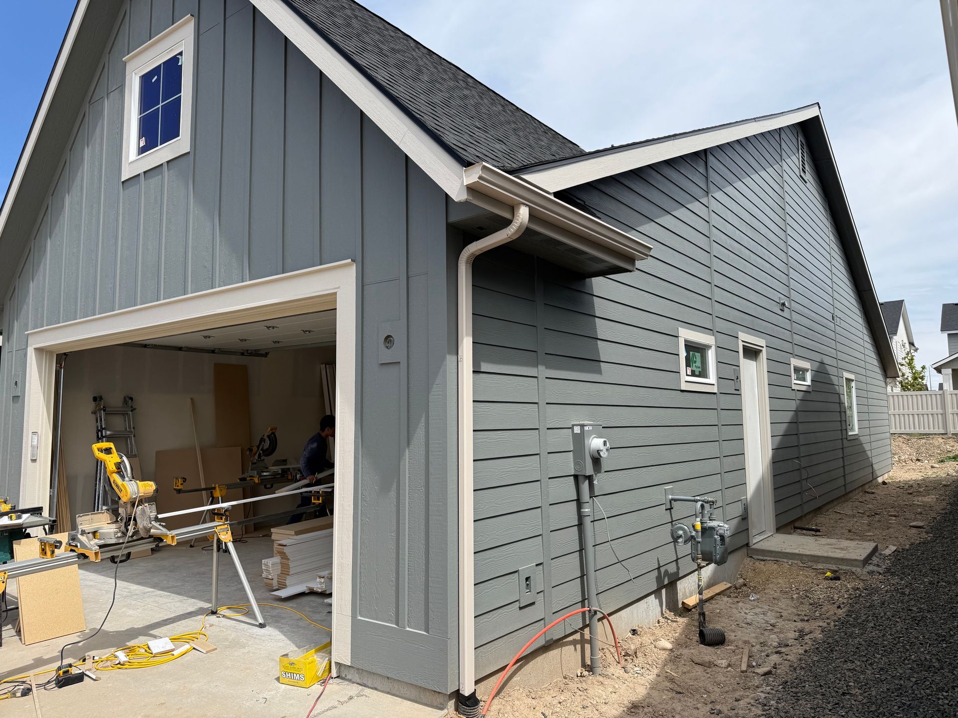 Gray siding on a garage under construction, with open door revealing tools.