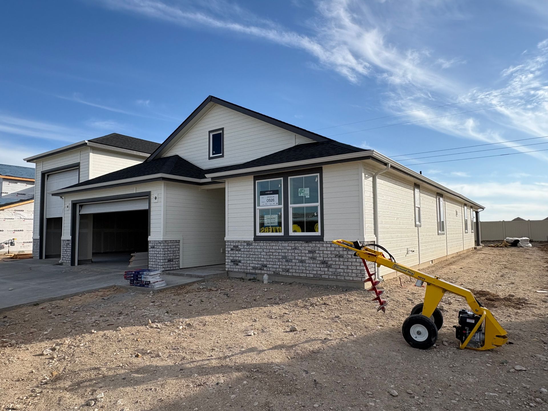 New house under construction with a yellow machine in front.