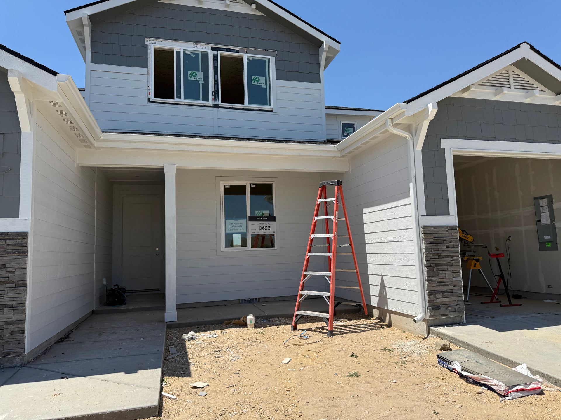 Two-story house under construction with a red ladder leaning against the wall.