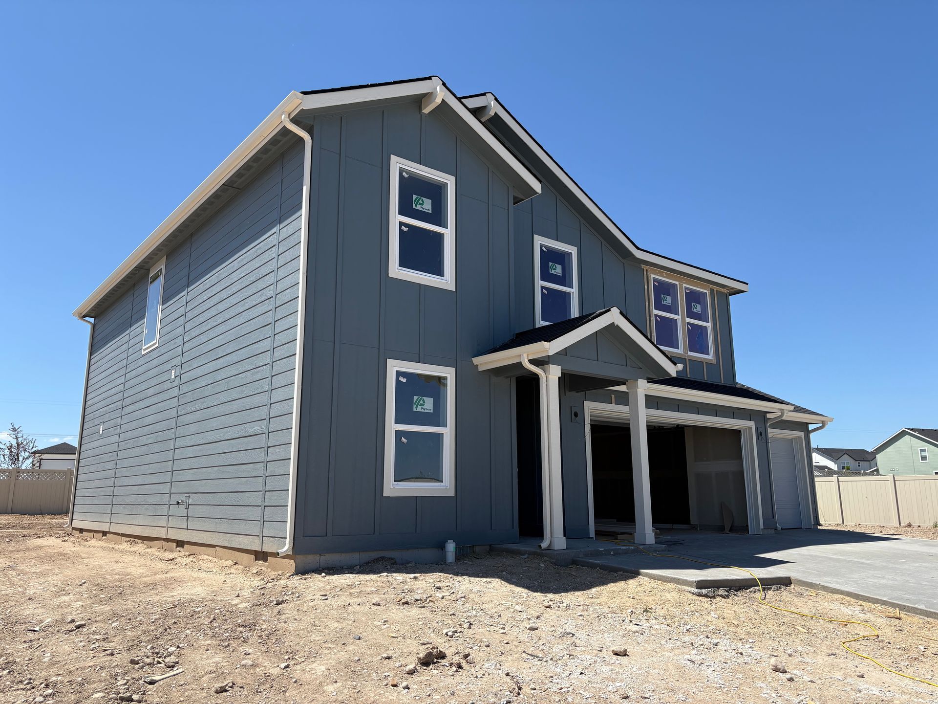Two-story blue house under construction with white trim and a clear blue sky.