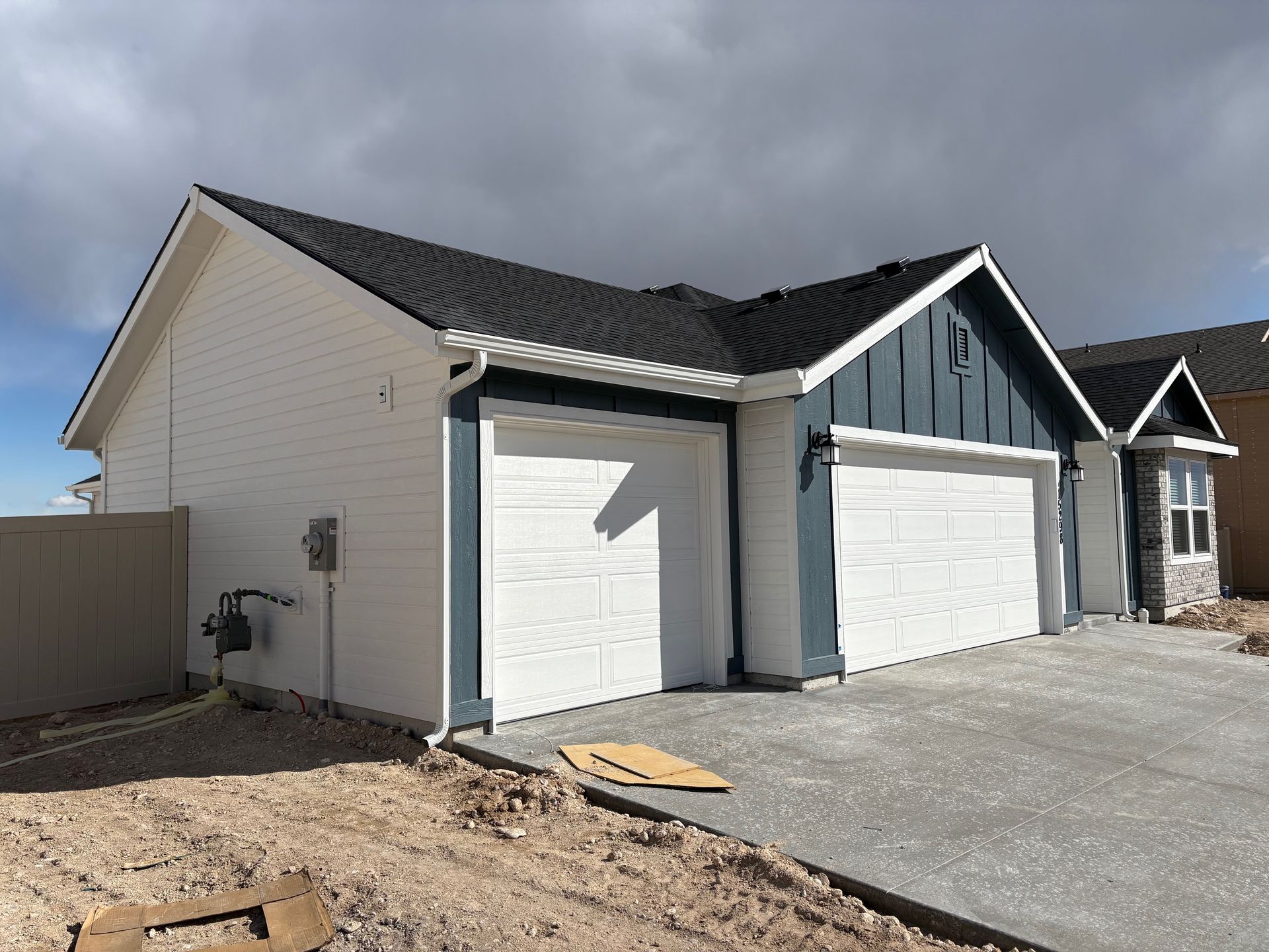 Garage with white siding and blue trim under a cloudy sky.
