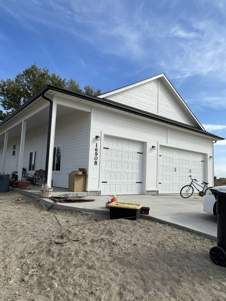 A white house with three garage doors and a bicycle parked in front of it.