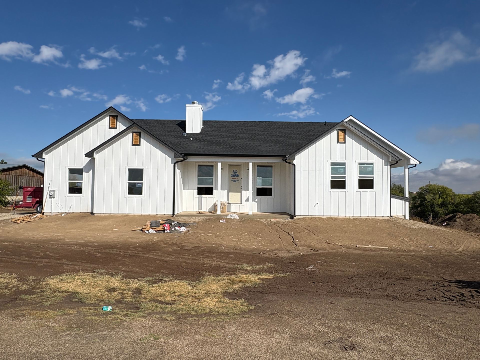 White farmhouse under construction on a sunny day.