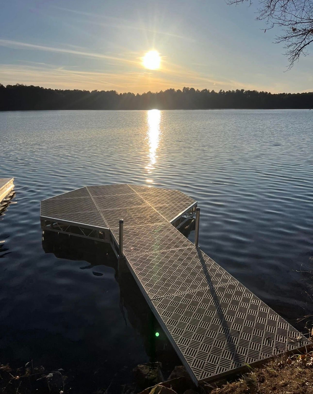 Metal fishing chair on a boat deck overlooking a lake and cloudy sky