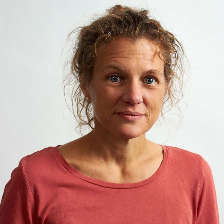 Eine Frau trägt ein rotes Shirt und lächelt in die Kamera